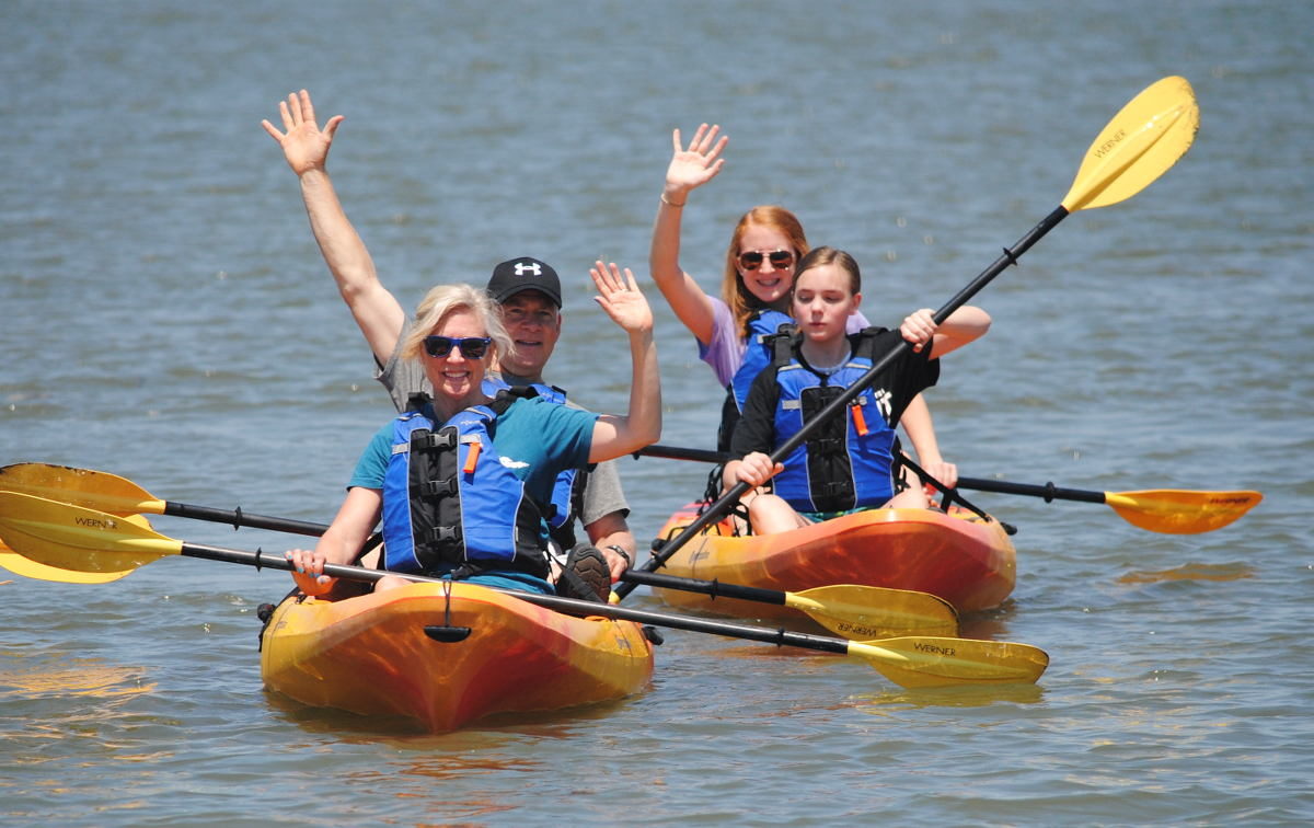 Happy family of kayakers waving.