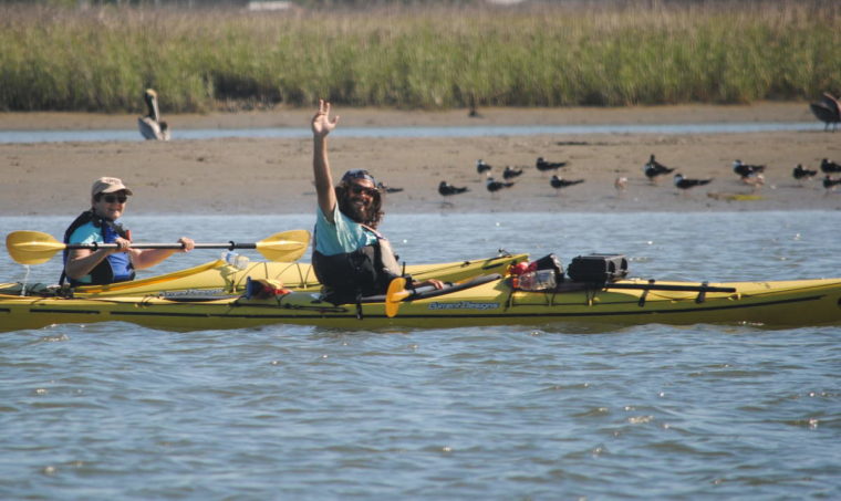 Kayak tour waving with birds in the background.