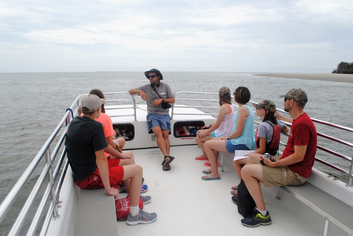 Tour guide explaining fossil history of SC to group on a boat.