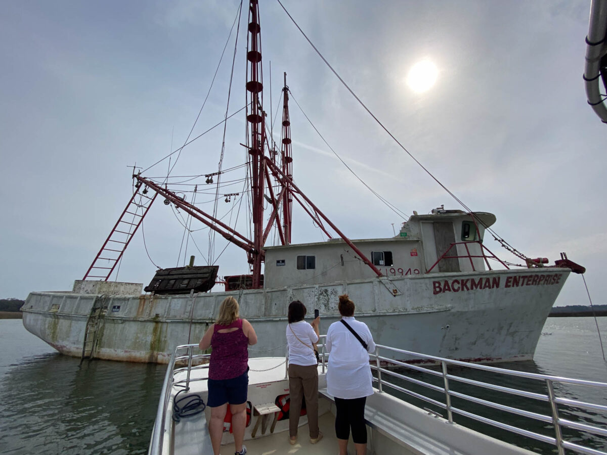 Women on Charleston lowcountry culture and history boat tour view an old fishing boat. 